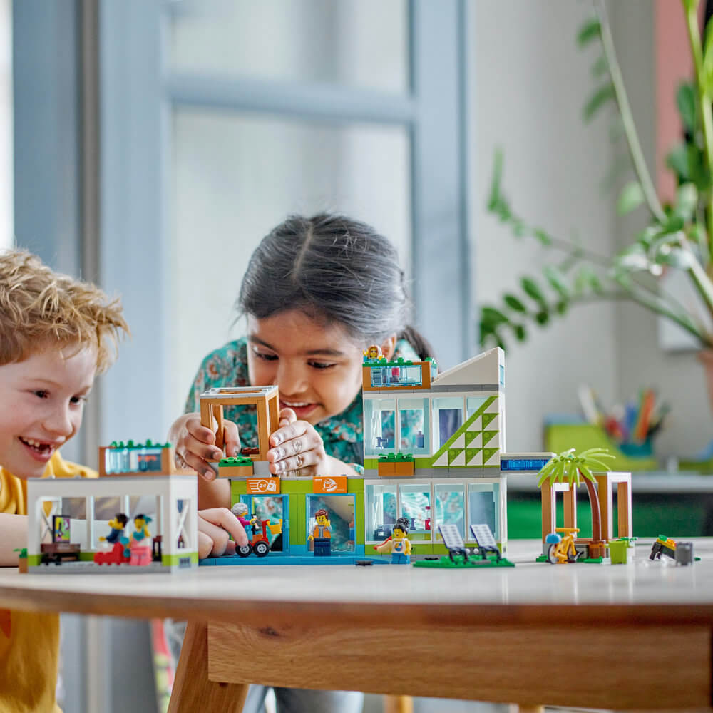 Two children playing with the LEGO® City Apartment Building 60365 Building Toy Set (688 Pieces)