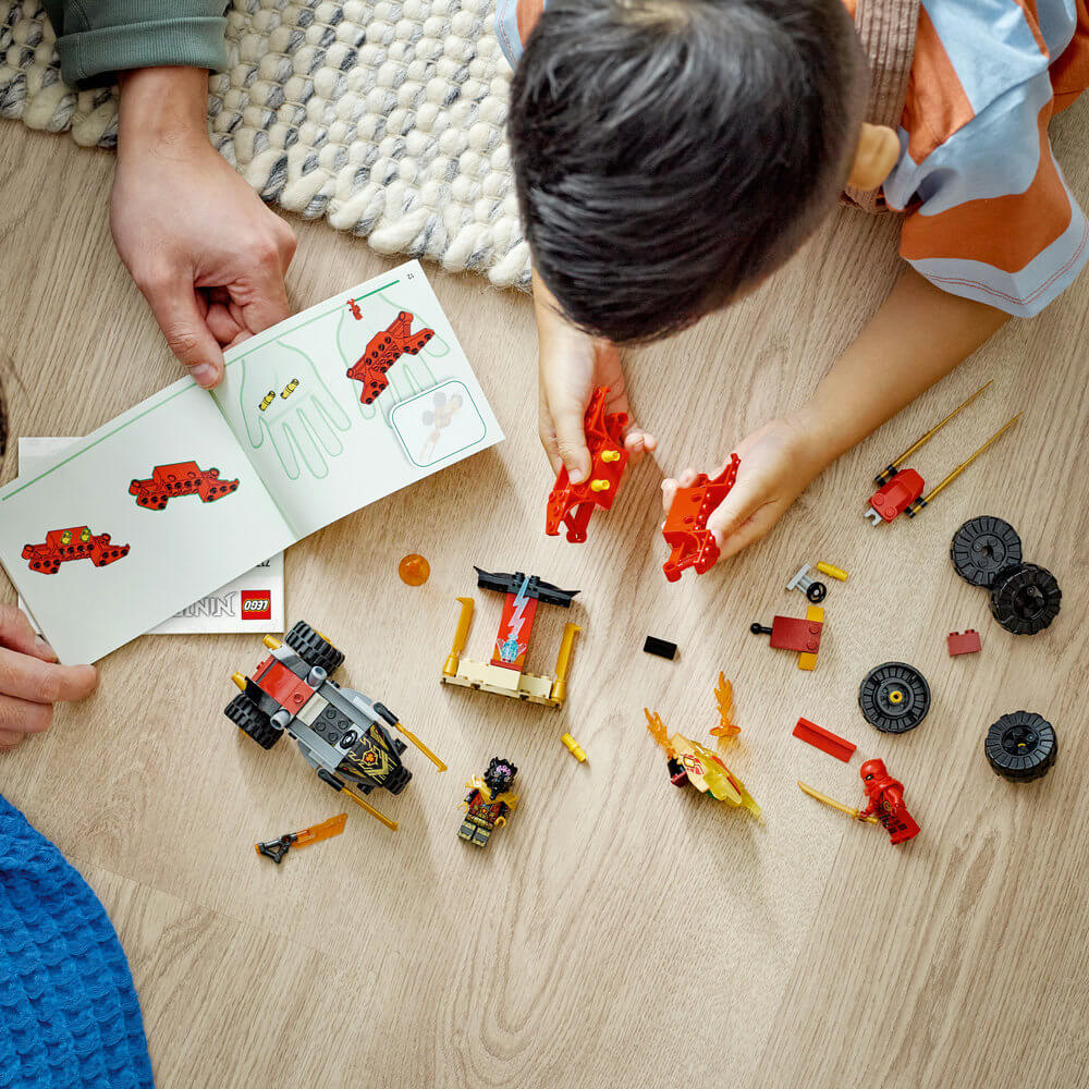 Two people working together following the directions to build the LEGO® NINJAGO® Kai and Ras’s Car and Bike Battle 71789 Building Toy Set (103 Pieces)