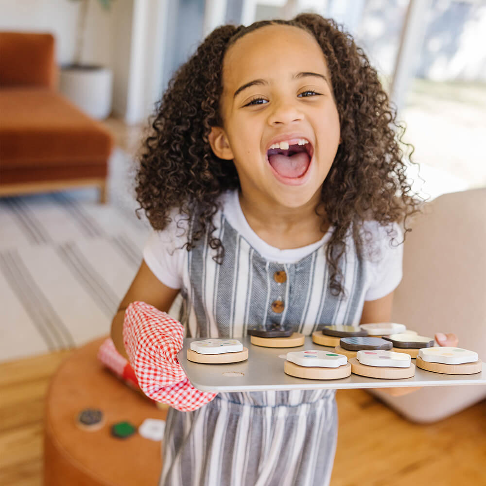 Girl holding a bake tray with cookies from the Melissa and Doug Slice and Bake Cookie Wooden Food Play Set