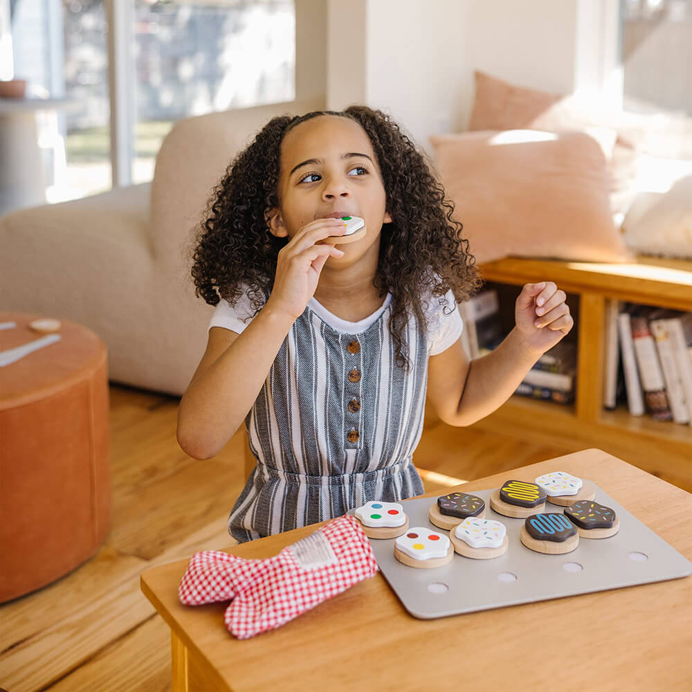 Girl pretending to eat a cookie from the Melissa and Doug Slice and Bake Cookie Wooden Food Play Set