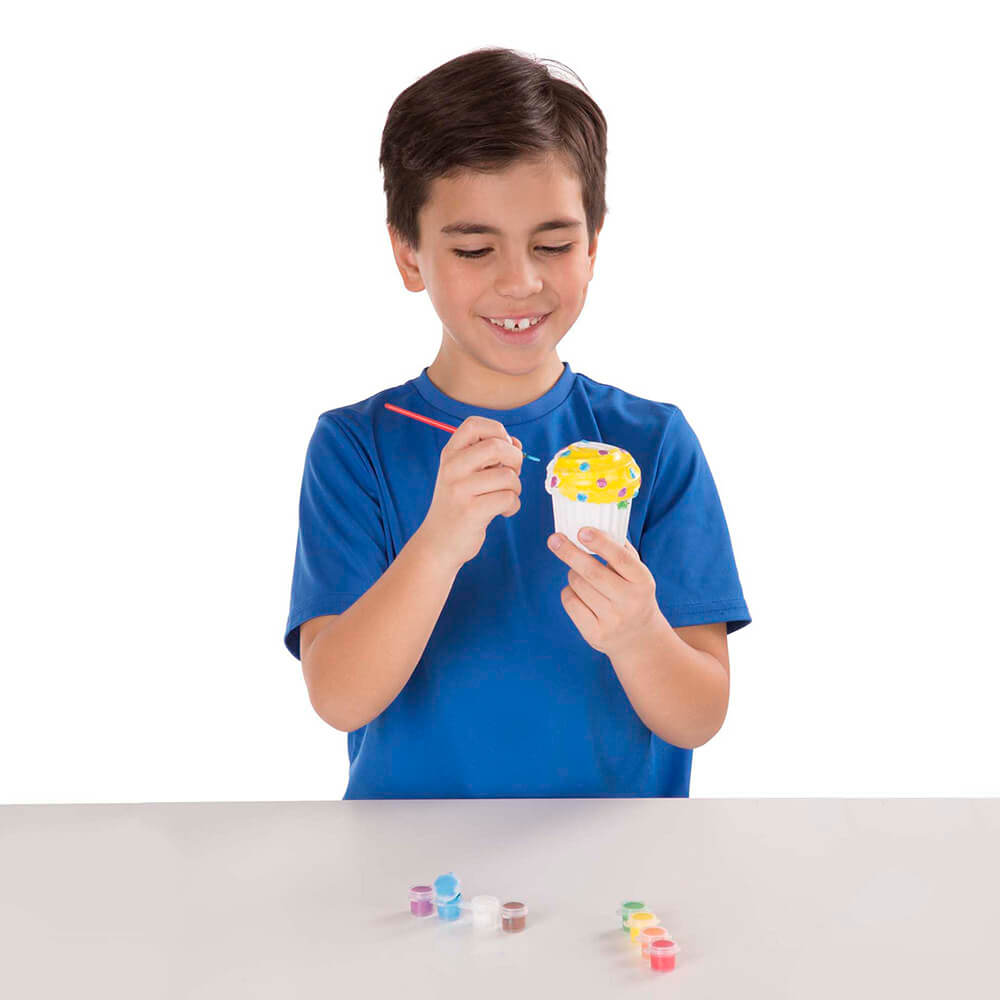 Boy holding his Melissa and Doug Created by Me! Cupcake Bank Craft Kit and painting it in his hand