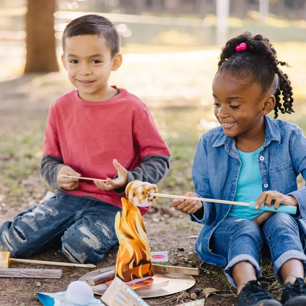 Boy wearing red and girl wearing denim playing the toy set Melissa and Doug Let's Explore Campfire S'Mores Play Set