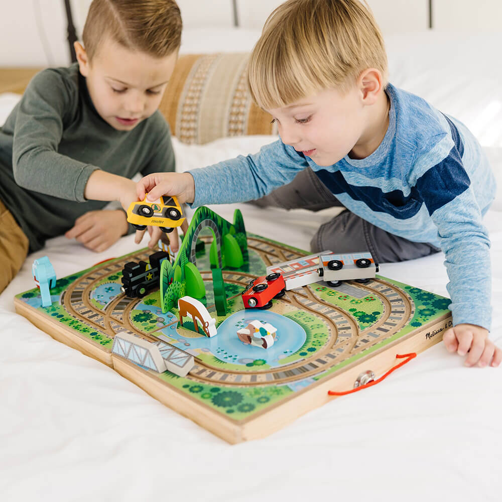 Two boys playing with the Melissa and Doug Take-Along Railroad Play Set