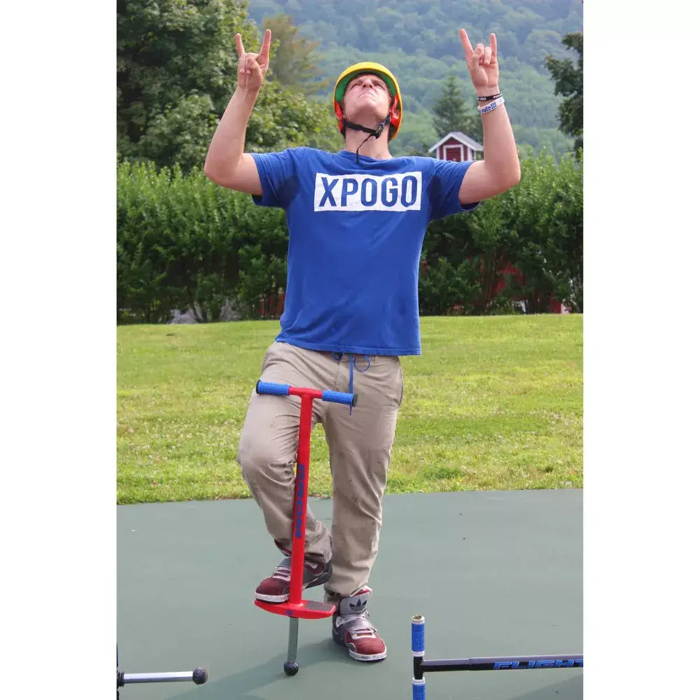 Man wearing blue shirt wearing yellow helmet using pogo stick