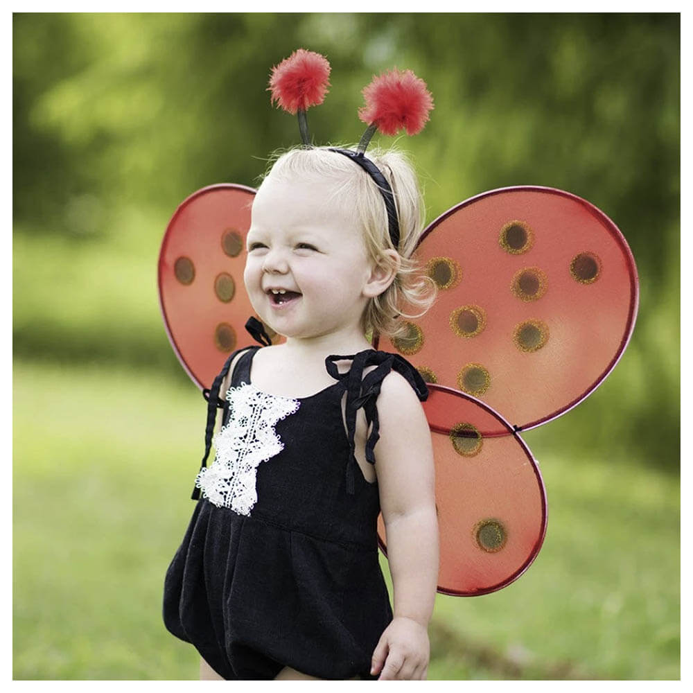 Front view of little girl wearing the Great Pretenders Ladybug Wings & Headband.